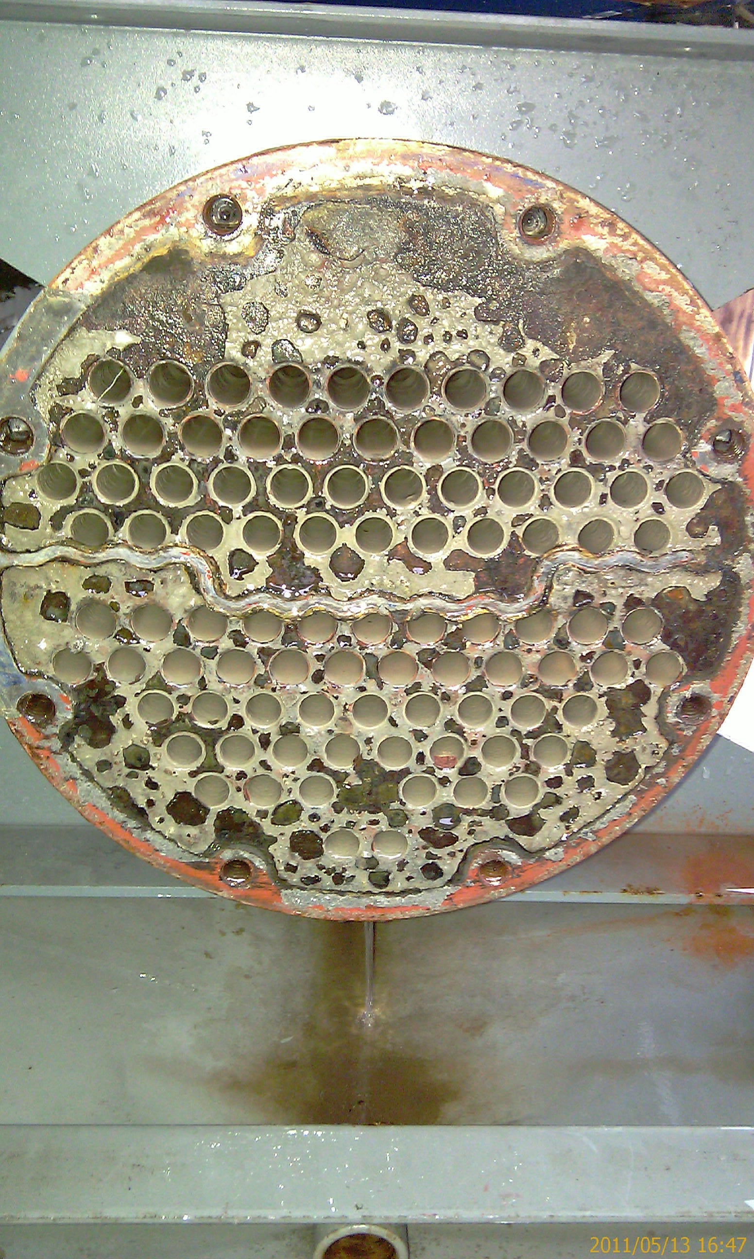 清洗前冷凝器管路內壁幾乎被灰白色矽酸鹽水垢與鐵鏽沉積覆蓋，流道變窄、局部接近堵塞的狀態